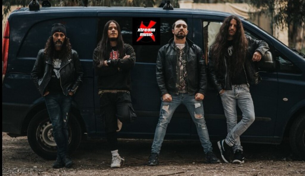 Fotografía de la banda Retador posando frente a una furgoneta, encapsulando el espíritu rebelde del thrash metal. Los cuatro integrantes lucen atuendos oscuros y actitud desafiante, característicos del género que representan. En el fondo, se vislumbra un entorno urbano que refuerza su esencia callejera y auténtica.