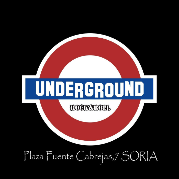 La imagen muestra un diseño gráfico con un estilo que recuerda a la señalización del metro de Londres, con un círculo central en rojo y una franja azul horizontal que lleva la palabra "UNDERGROUND" en letras mayúsculas de color blanco. Debajo de esta franja, en letras más pequeñas, se lee "ROCK&ROLL", indicando el género musical o la temática del lugar.  El fondo de la imagen es negro, lo que resalta aún más los colores rojo, blanco y azul del diseño. En la parte inferior de la imagen, sobre el fondo negro, hay texto en color blanco que dice "Plaza Fuente Cabreras, 7 SORIA", proporcionando la dirección del establecimiento que el logotipo representa. El diseño sugiere un ambiente urbano y contemporáneo, posiblemente un bar o club dedicado a la música rock and roll ubicado en Soria.