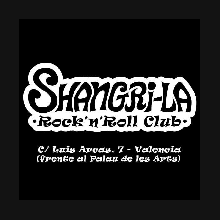 La imagen presenta un anuncio en blanco y negro para "Shangri-La Rock'n'Roll Club". El nombre "SHANGRI-LA" está en la parte superior, en grandes letras mayúsculas de estilo retro con sombreado, lo que les da una apariencia en 3D. Debajo, en una tipografía más pequeña y entre dos puntos, está la frase "Rock'n'Roll Club", estableciendo la temática del lugar.  En la parte inferior del anuncio, en letras más pequeñas y sencillas, se proporciona la dirección "C/ Luis Arceos, 7 - Valencia" y se añade una nota de ubicación "(frente al Palau de les Arts)". El diseño transmite una sensación vintage y se asocia con la música rock and roll y la cultura de los años 50 o 60, sugerente de un ambiente clásico de club de rock. El contraste del blanco sobre negro asegura que el texto sea destacado y fácilmente legible.